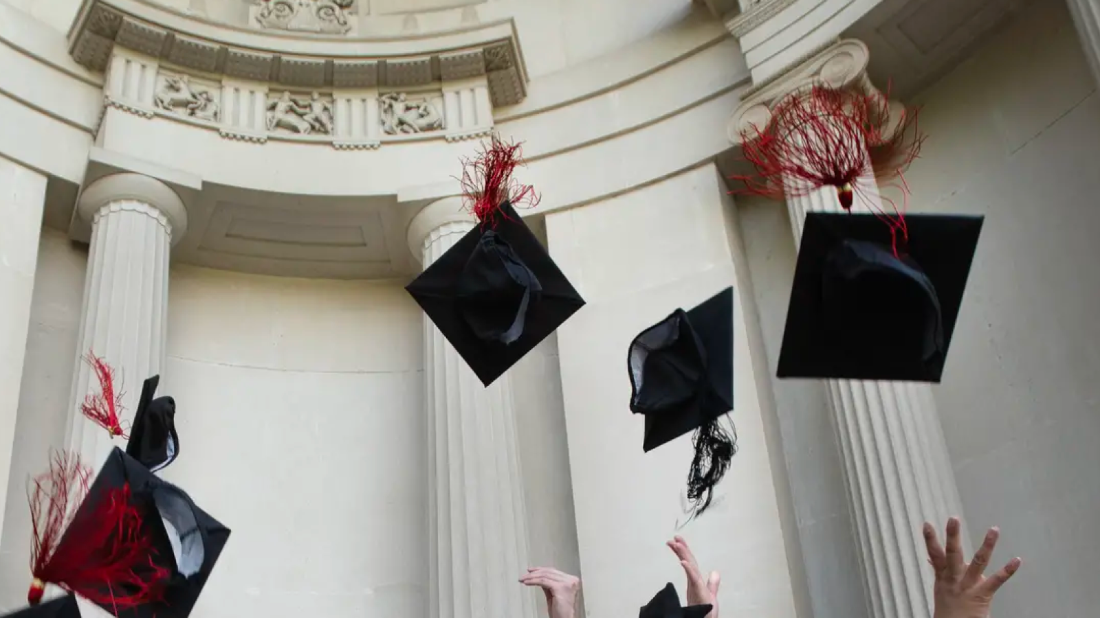 Hands throwing graduation caps in the air