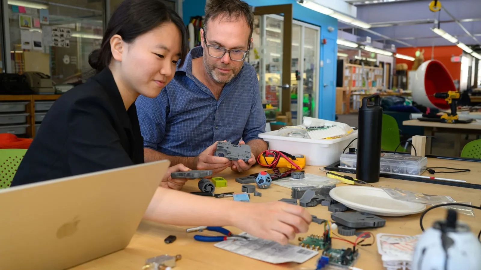 A student and a professor look at pieces of an unassembled machine