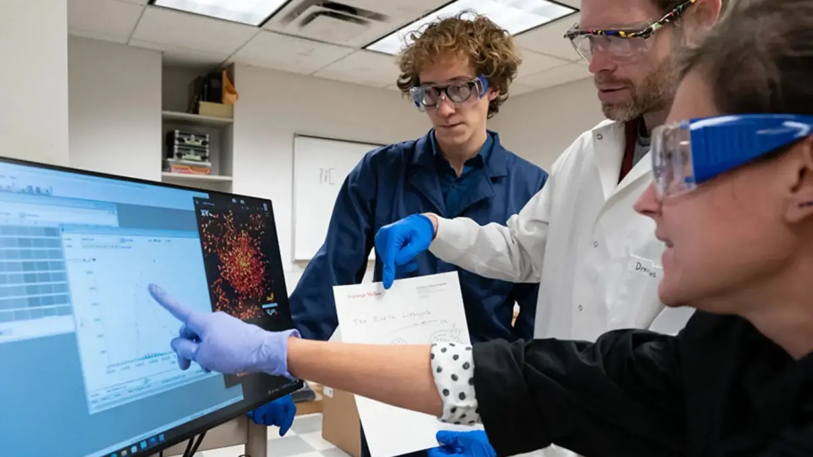 Three researchers in a lab looking at data on a computer