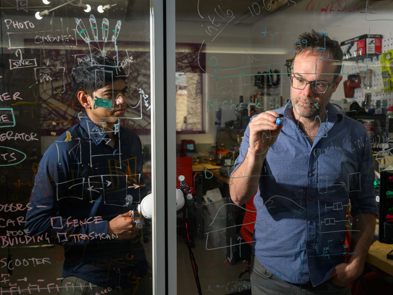 A student and a professor are working through calculations on a window