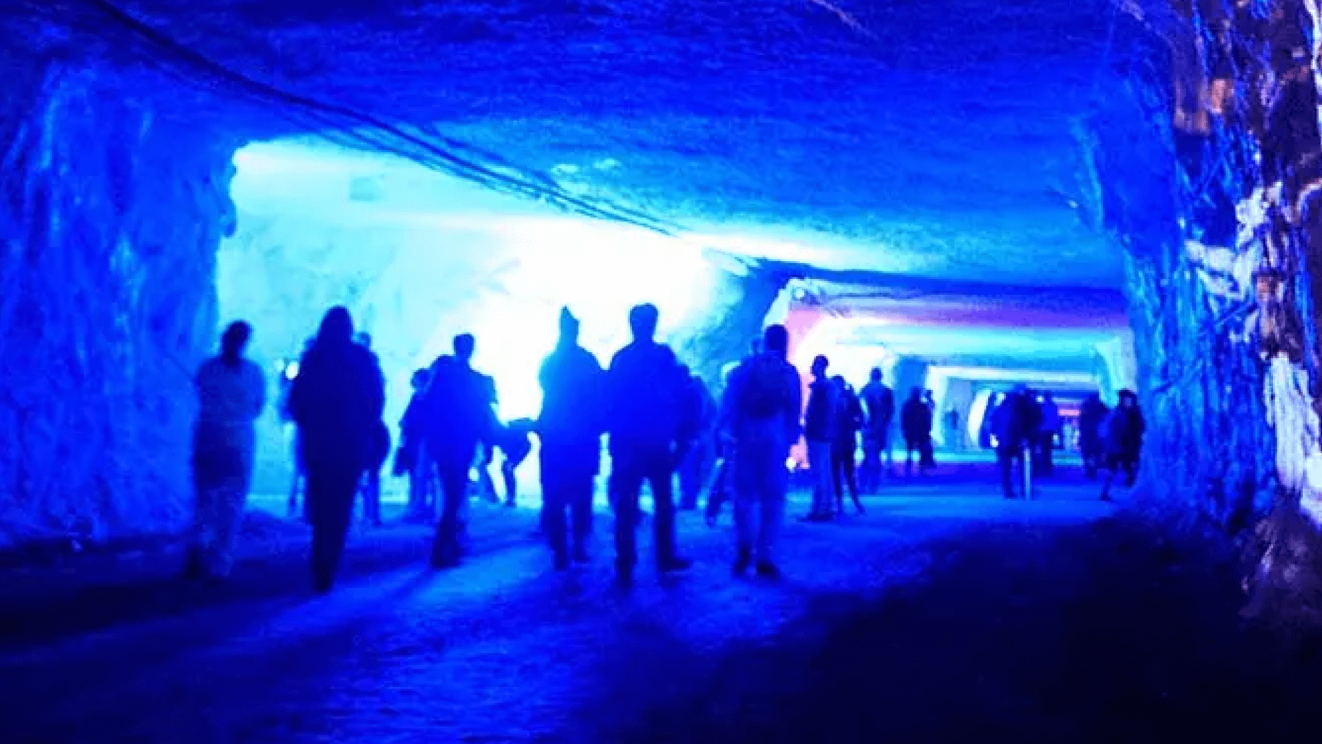 People walking underground with images and patterns projected on the walls
